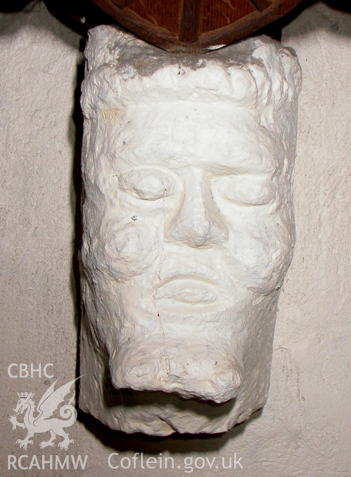 Carved stone head at east end, to north.