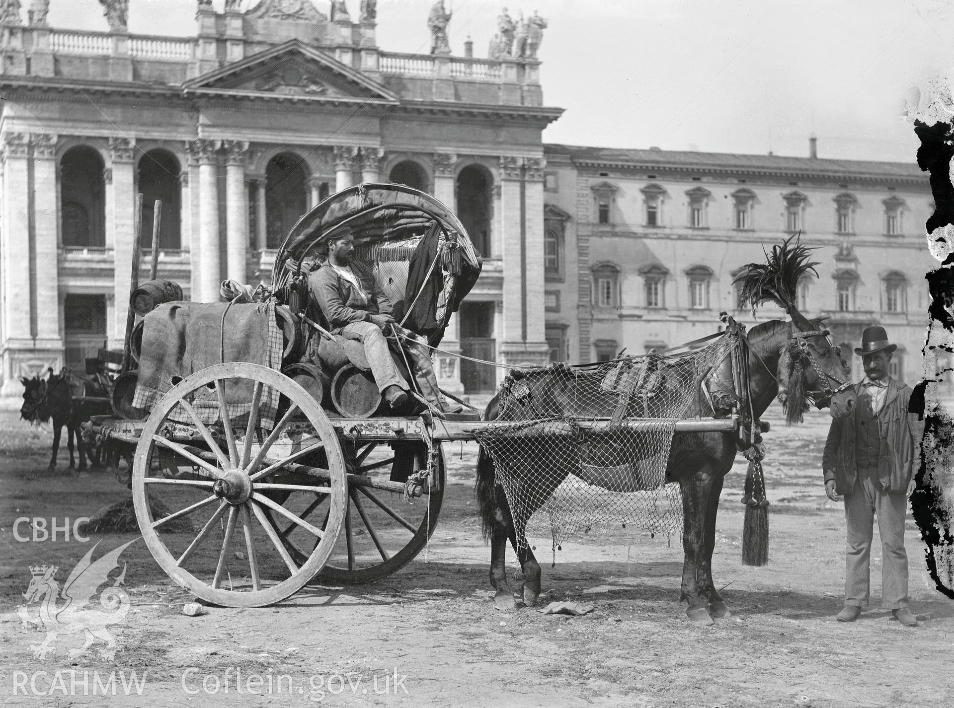 Black and white image dating from c.1910 showing a decorated horse and carriage outside a substantial building, probably European,, taken by Emile T. Evans.