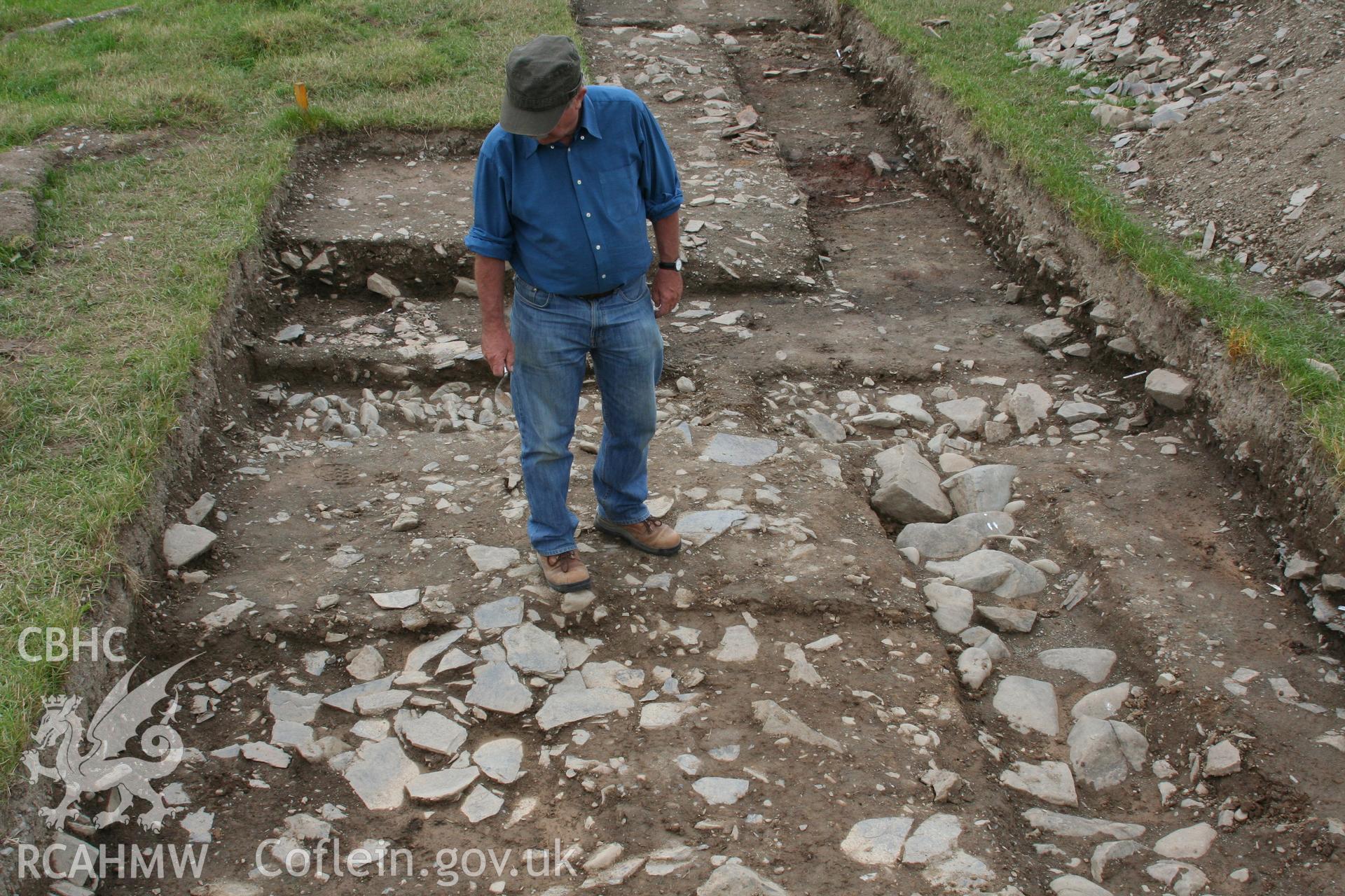 Abermagwr Roman villa excavations, July 2010. Trench A from the north following excavation. Figure stands in exterior angle of villa formed by rear (north) villa wall footings crossing left to right and footings of Room 6 to right.