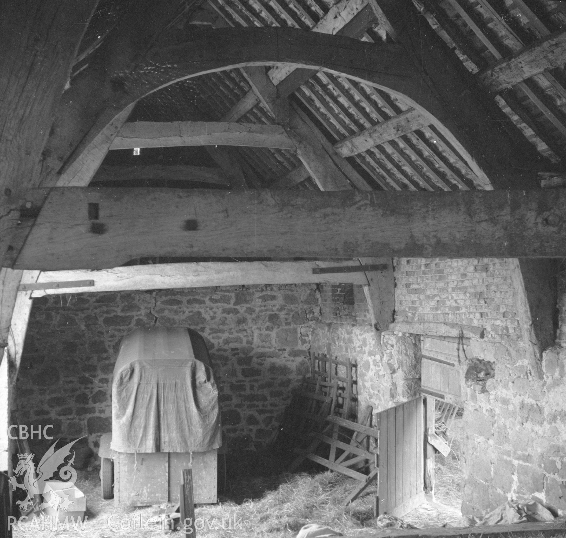 Digital copy of a black and white nitrate negative showing cruck timbers in the barn at Rhual.