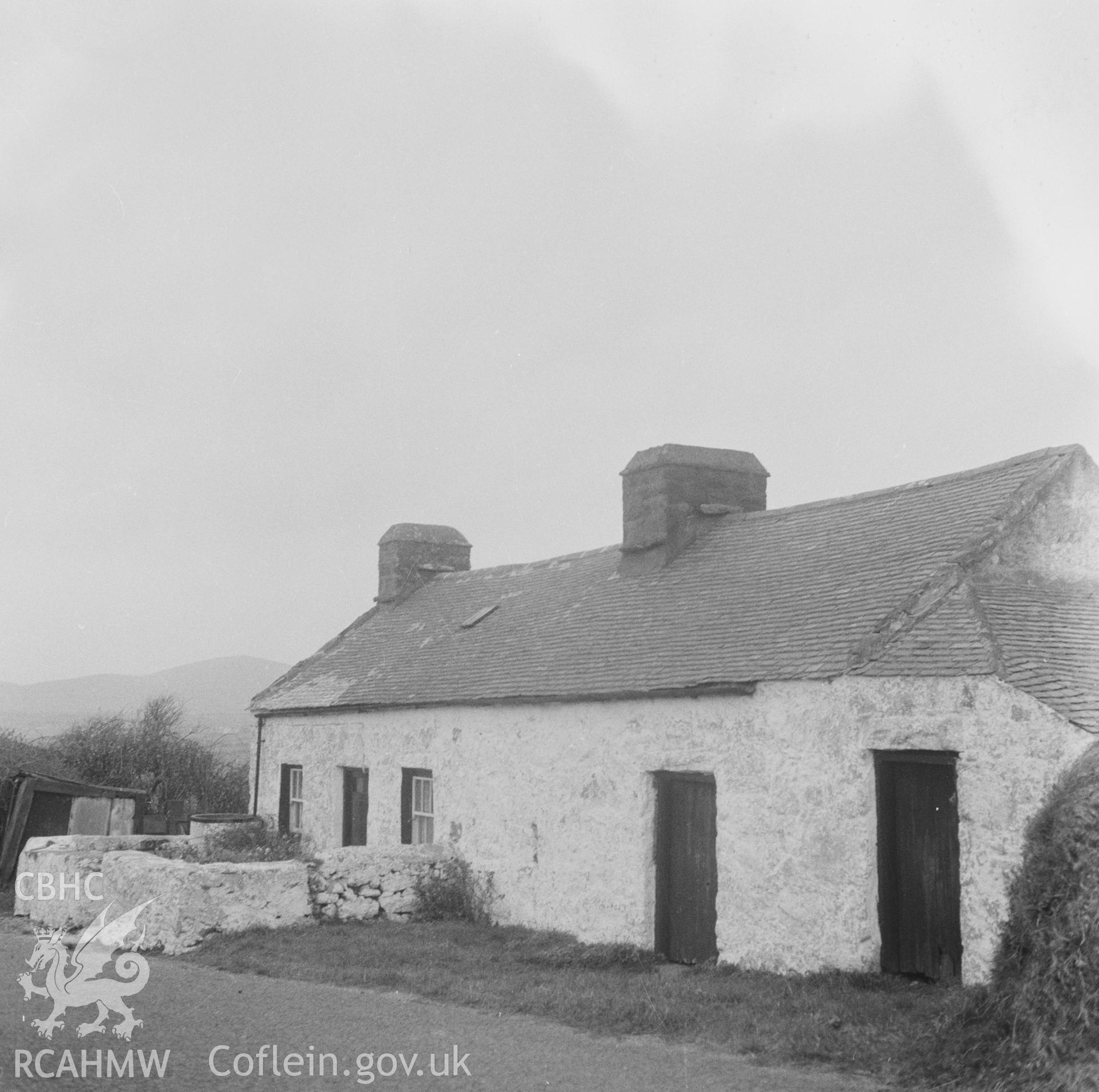 Digital copy of a black and white nitrate negative showing an exterior view of unidentified cottages, captioned 'Caernarfon Cottages'.