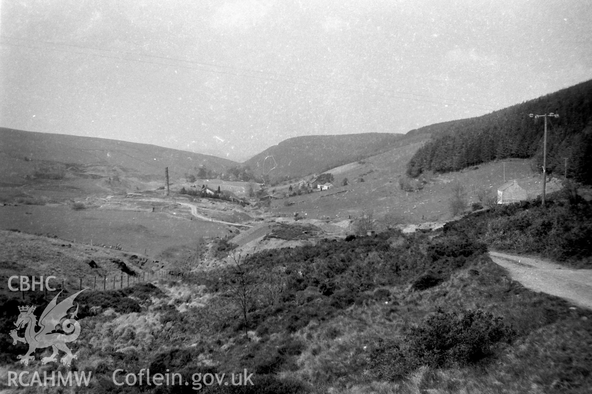 Digitised black and white photograph showing distant view of Cwmsymlog, including the masonry chimney stack associated with East Darren Lead Mine. Photographed by Martin Davies as part of his Bachelor of Architecture at the University of Nottingham, 1979.