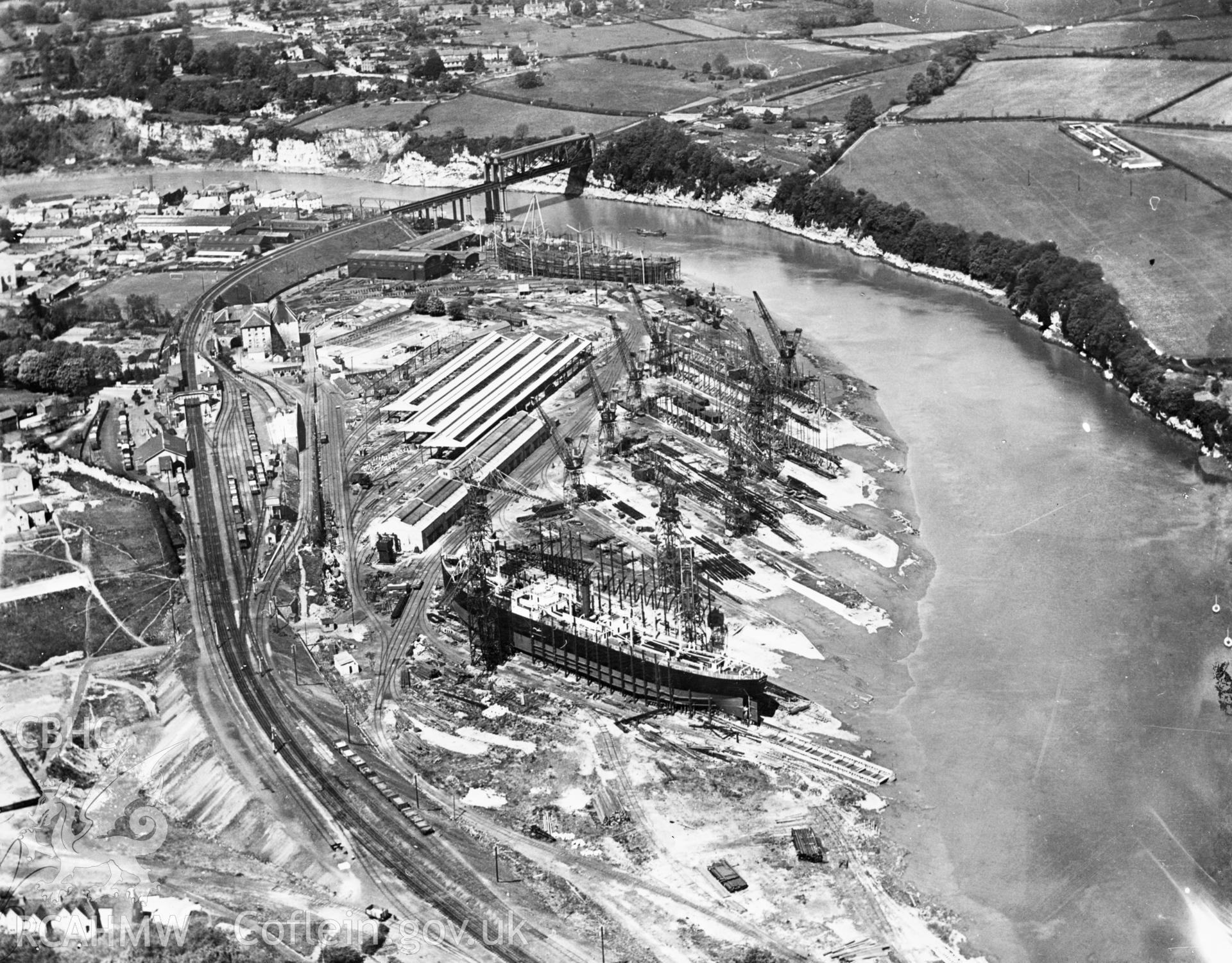 View of Chepstow showing ship building in the National Ship Yard, engineering works and tubular suspension bridge. Oblique aerial photograph.