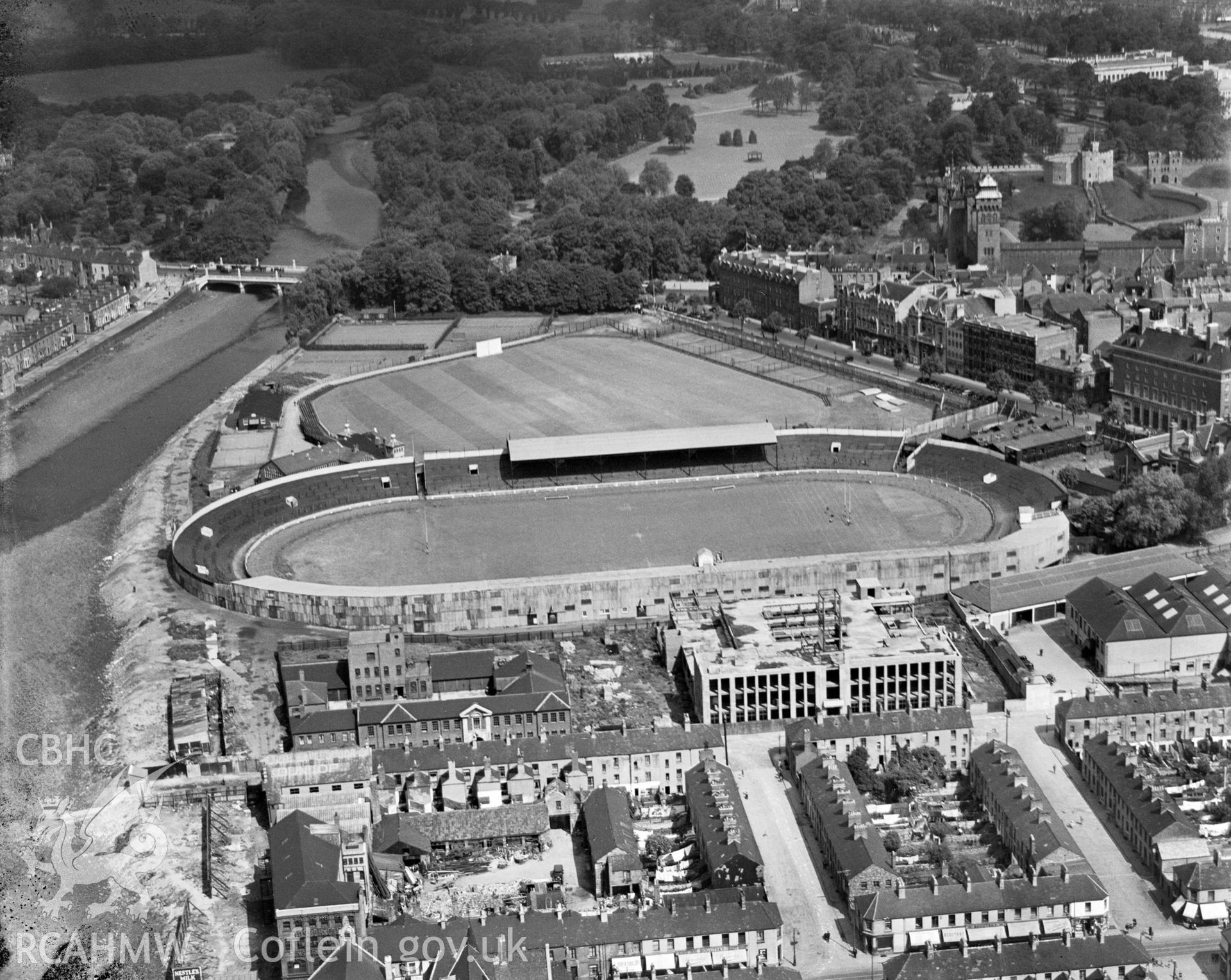 Digital copy of a black and white, oblique aerial photograph of Cardiff Arms Park, Cardiff. The photograph shows the view from the South East, showing Temperance Town in the foreground before its demolition by the Cardiff Corporation in 1937.