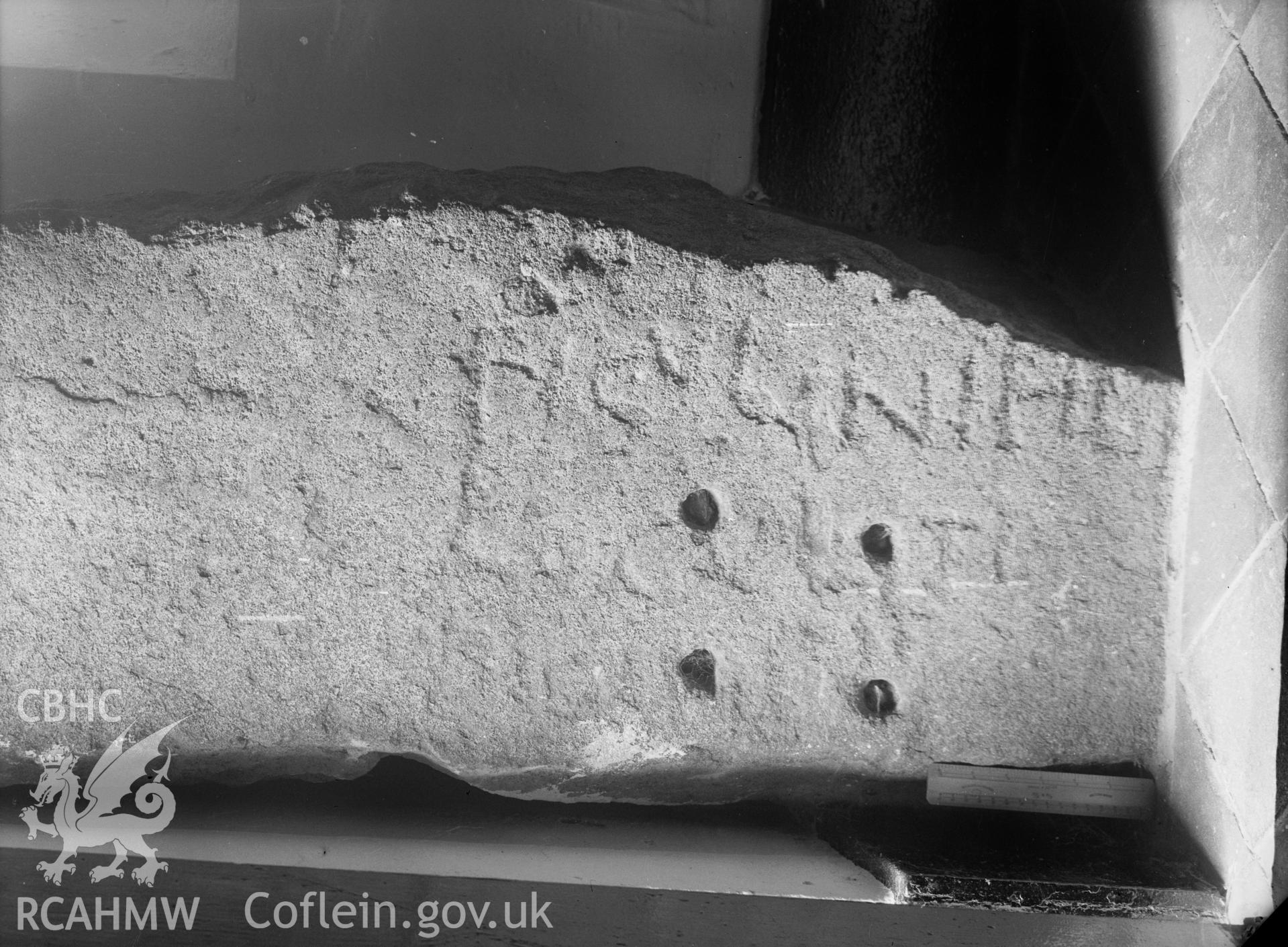 Digital copy of a black and white nitrate negative showing A pillar stone, formerly used as a churchyard gatepost and now preserved in the church porch, bears the inscription:                           FIGVLINI FILI/LOCVLITI/HIC IACIT