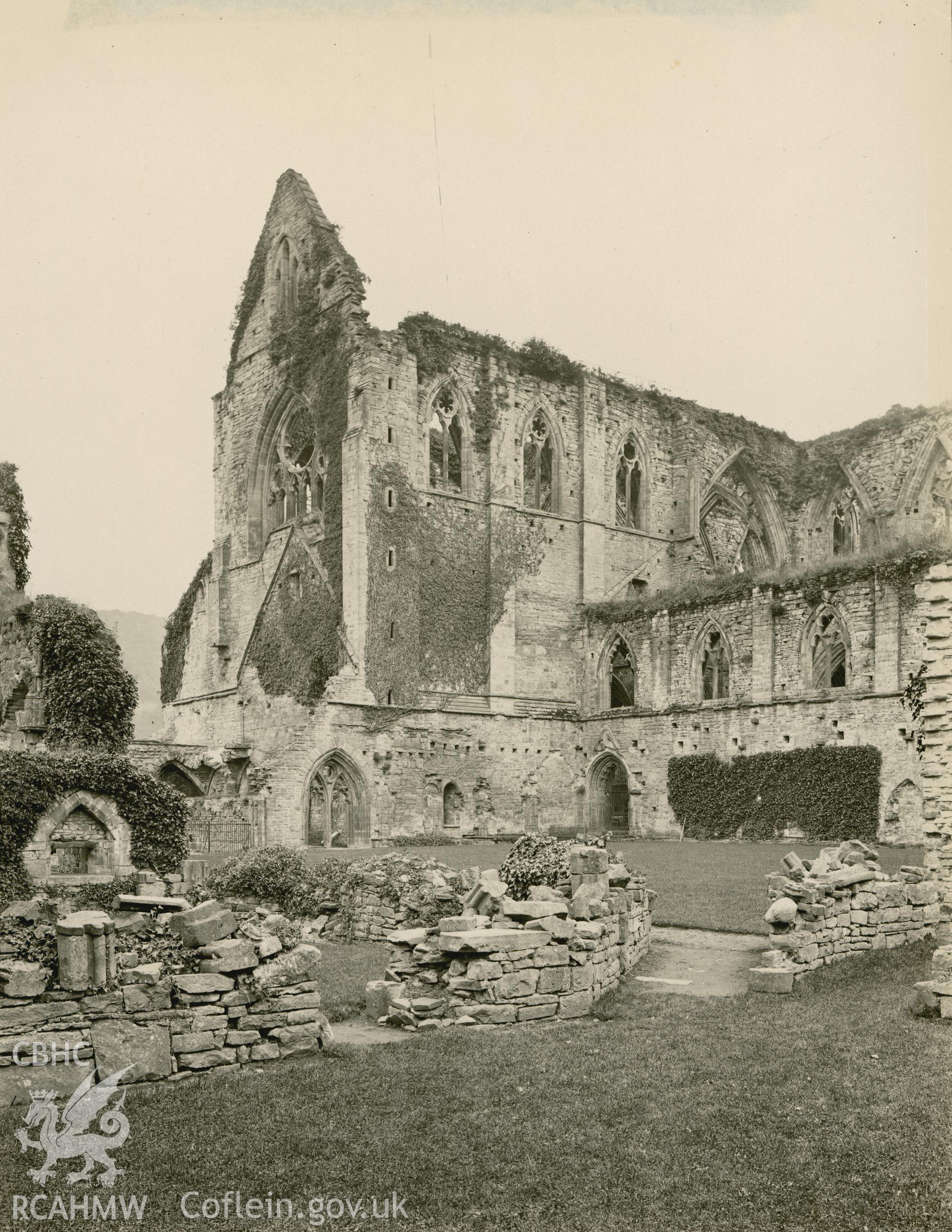 Digital copy of an early National Buildings Record photograph showing an exterior view of Tintern Abbey across the cloister looking southeast.