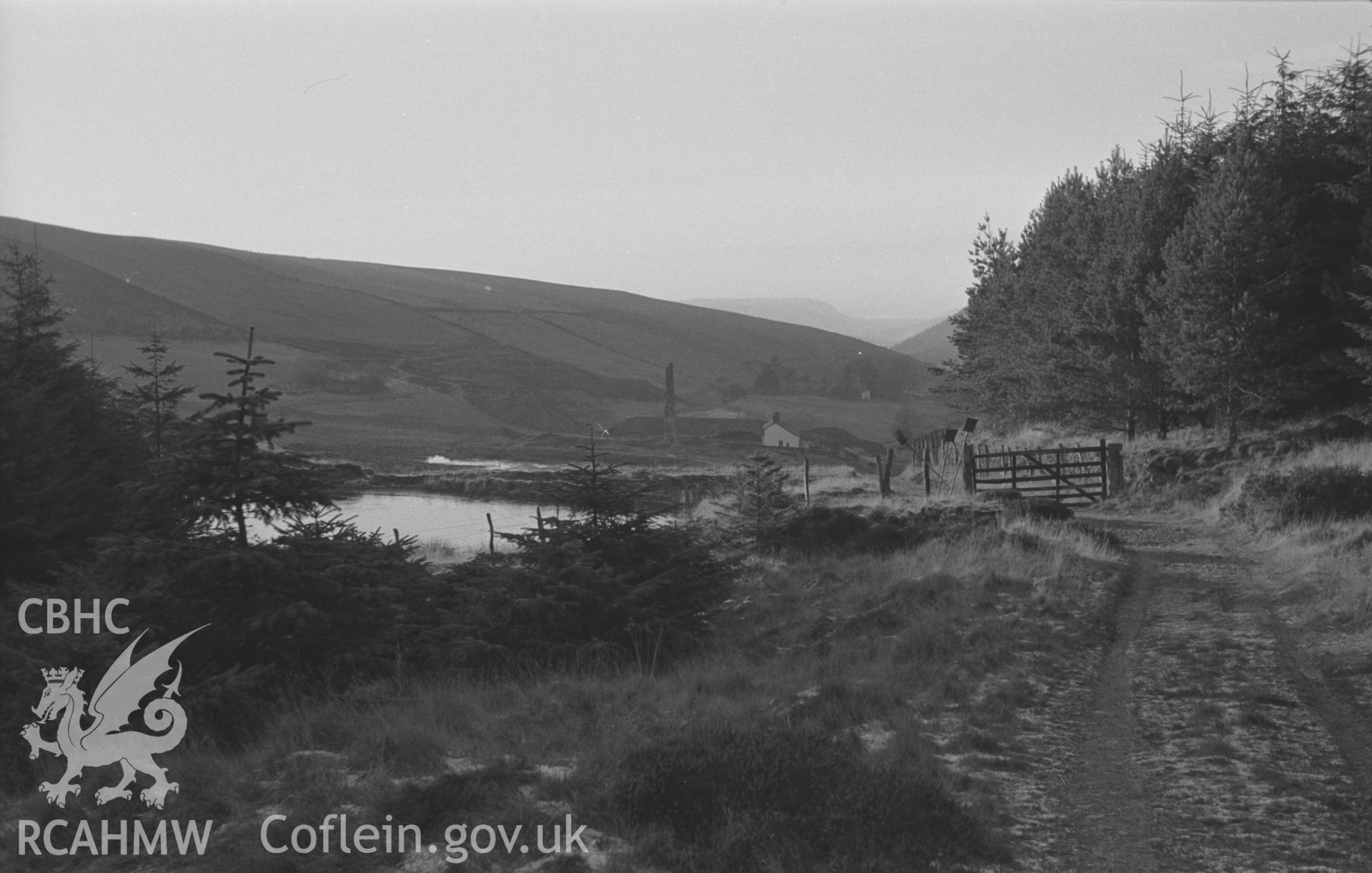 Black and White photograph showing view of the mine pools and old chimney of Cwmsymlog Mine from the old track just below Blaen-Cwm-Symlog, at 1000ft. Photographed by Arthur Chater in December 1962 from Grid Reference SN 704 838, looking west.