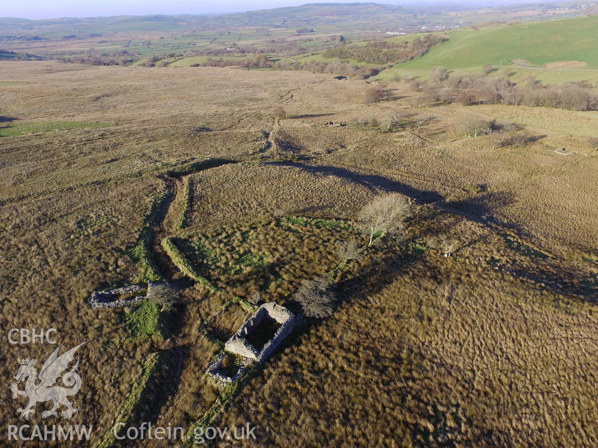 Aerial view of the remains of Tynewydd stone cottage and the ruined drystone outbuilding to the west, south west of Bryneithinog farm, Ystrad Fflur. Colour photograph taken by Paul R. Davis on 18th November 2018.