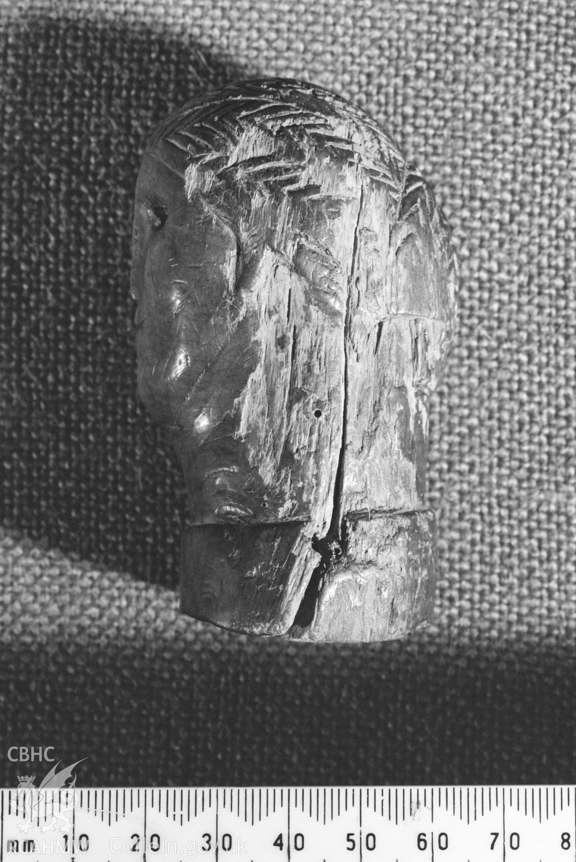 Digital copy of a black and white negative  showing a carved wooden head from Llanio Roman Fort.