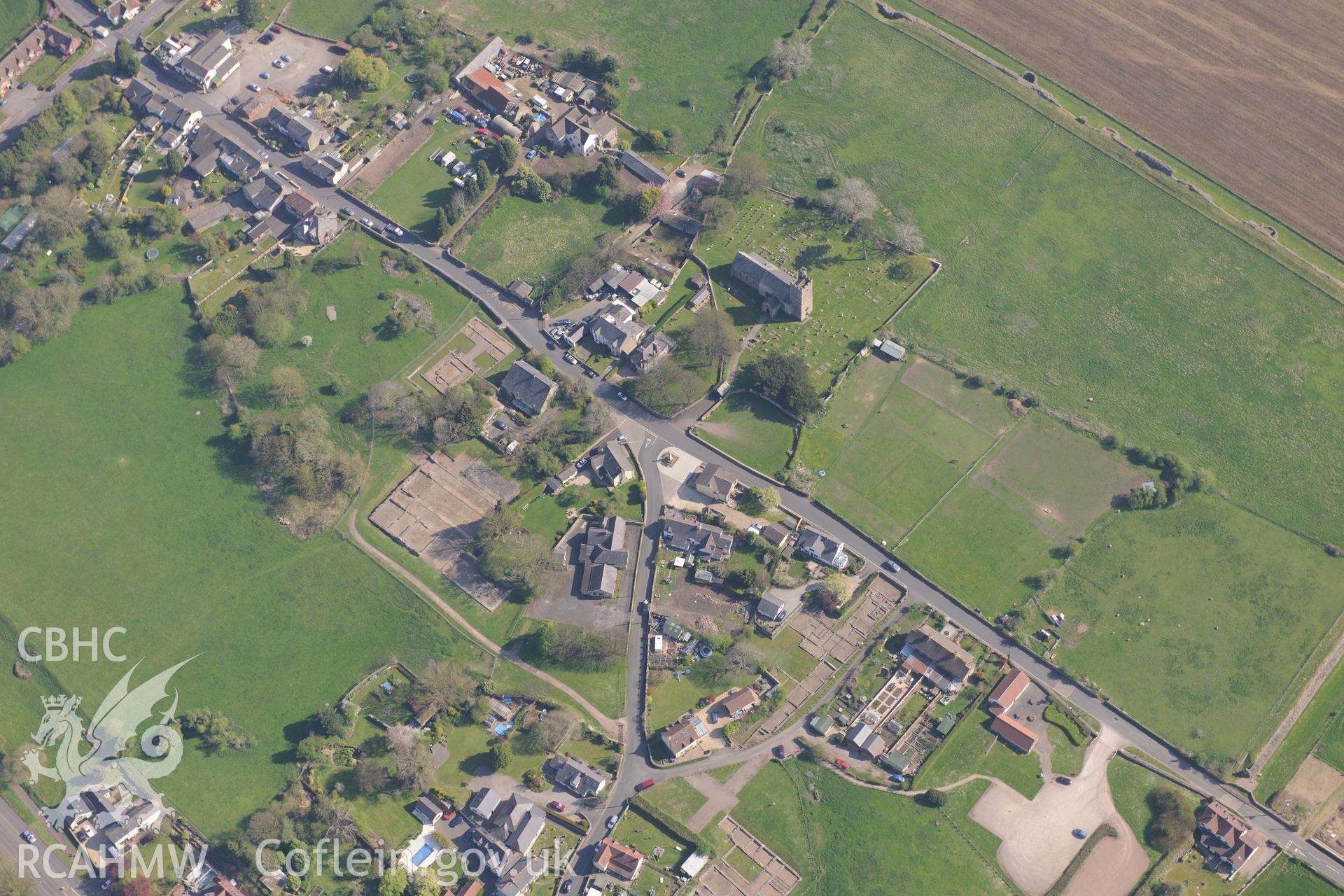 Caerwent village and Roman city including views of the Roman Amphitheatre and Basilica and Forum; St. Stephen's Church; Caerwent House; Great House and West Gate Farm. Oblique aerial photograph taken during the Royal Commission's programme of archaeological aerial reconnaissance by Toby Driver on 21st April 2015.