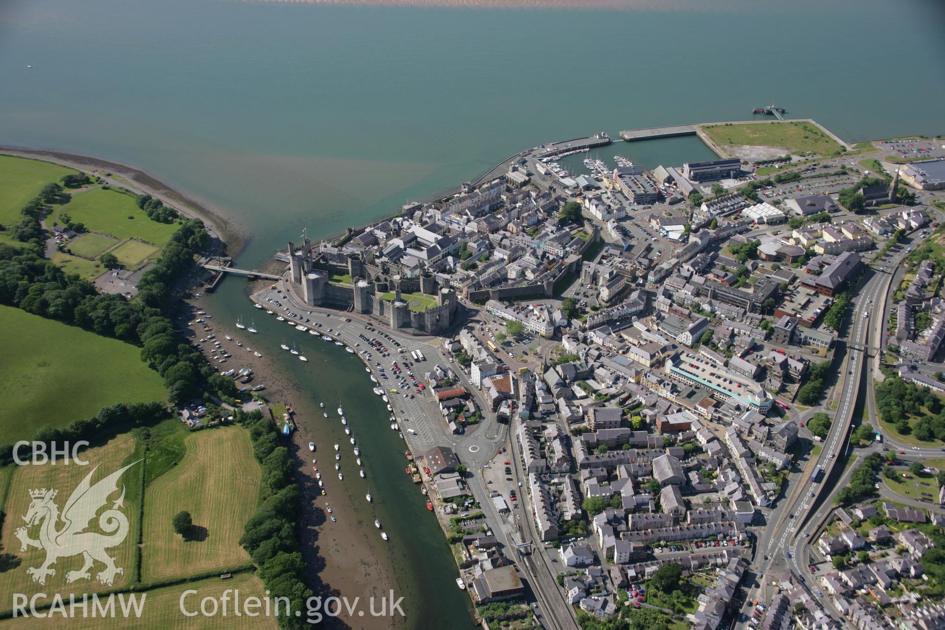 RCAHMW colour oblique aerial photograph of Caernarfon Castle and the walled town from the south-east. Taken on 14 June 2006 by Toby Driver.