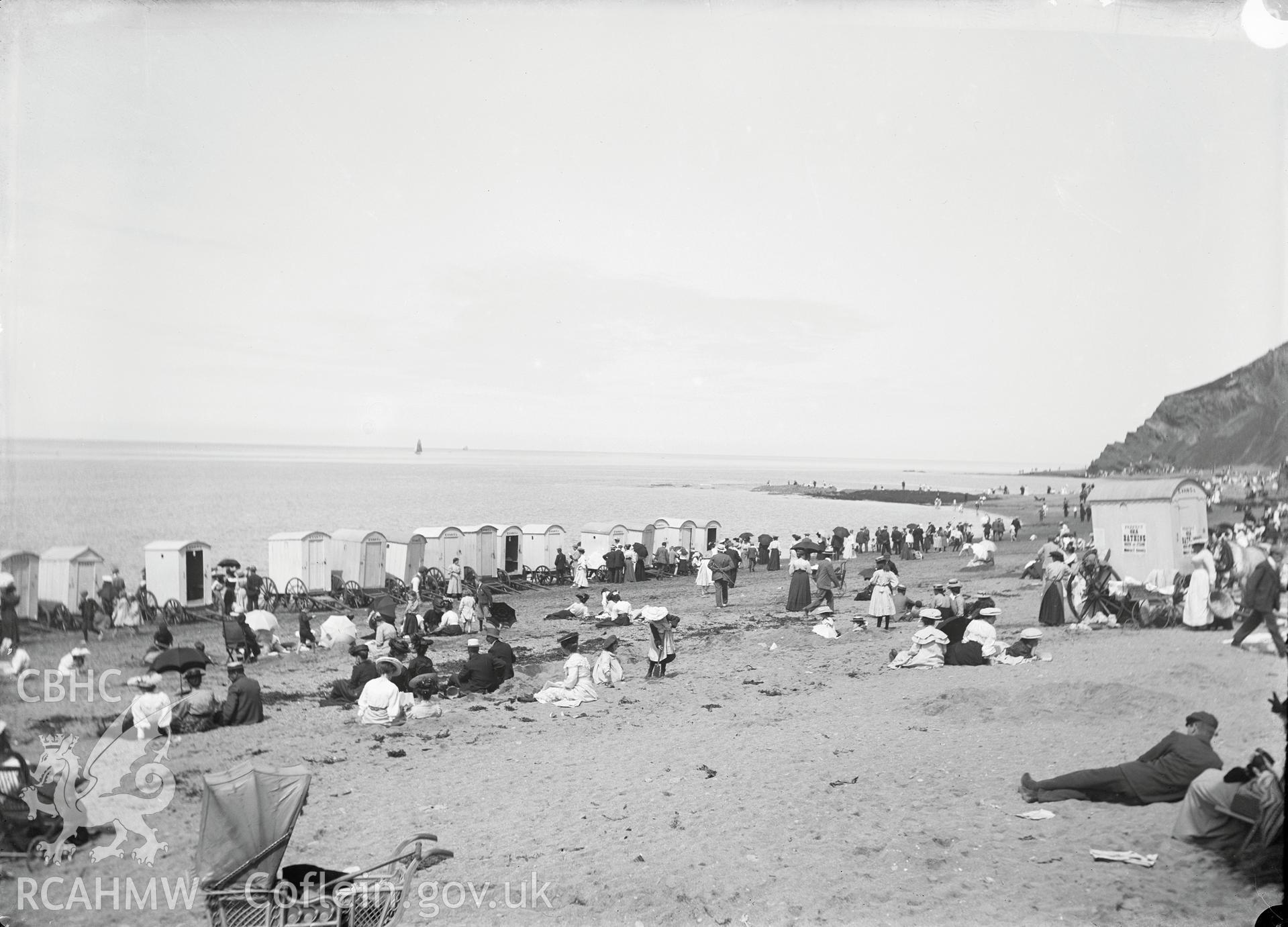 Black and white image dating from c.1910 showing a busy beach scene at Aberystwyth Castle,  taken by Emile T. Evans.