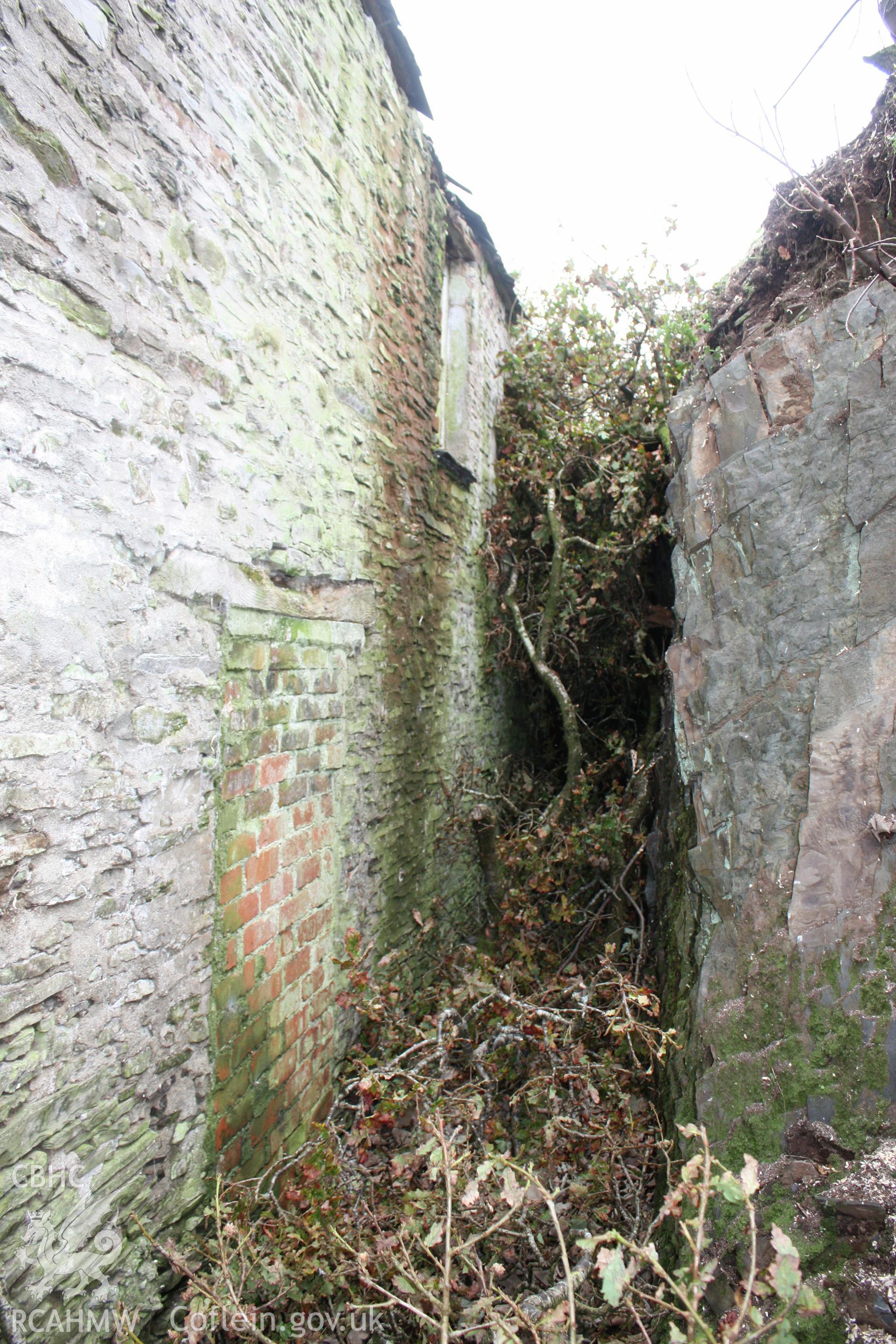 Exterior, view of rear blocked doorway to cottage and rock face.