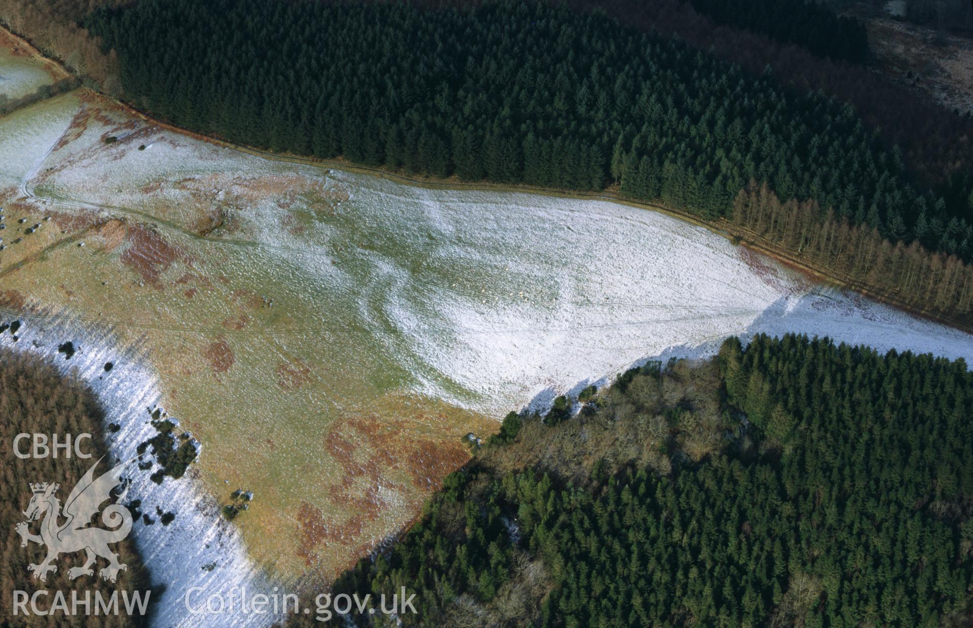 RCAHMW colour slide aerial photograph of Allt Aber Mangoed, defended enclosure, under drifting snow revealing earthworks outside enclosure (stereo colour). Taken by Toby Driver on 31/01/2003
