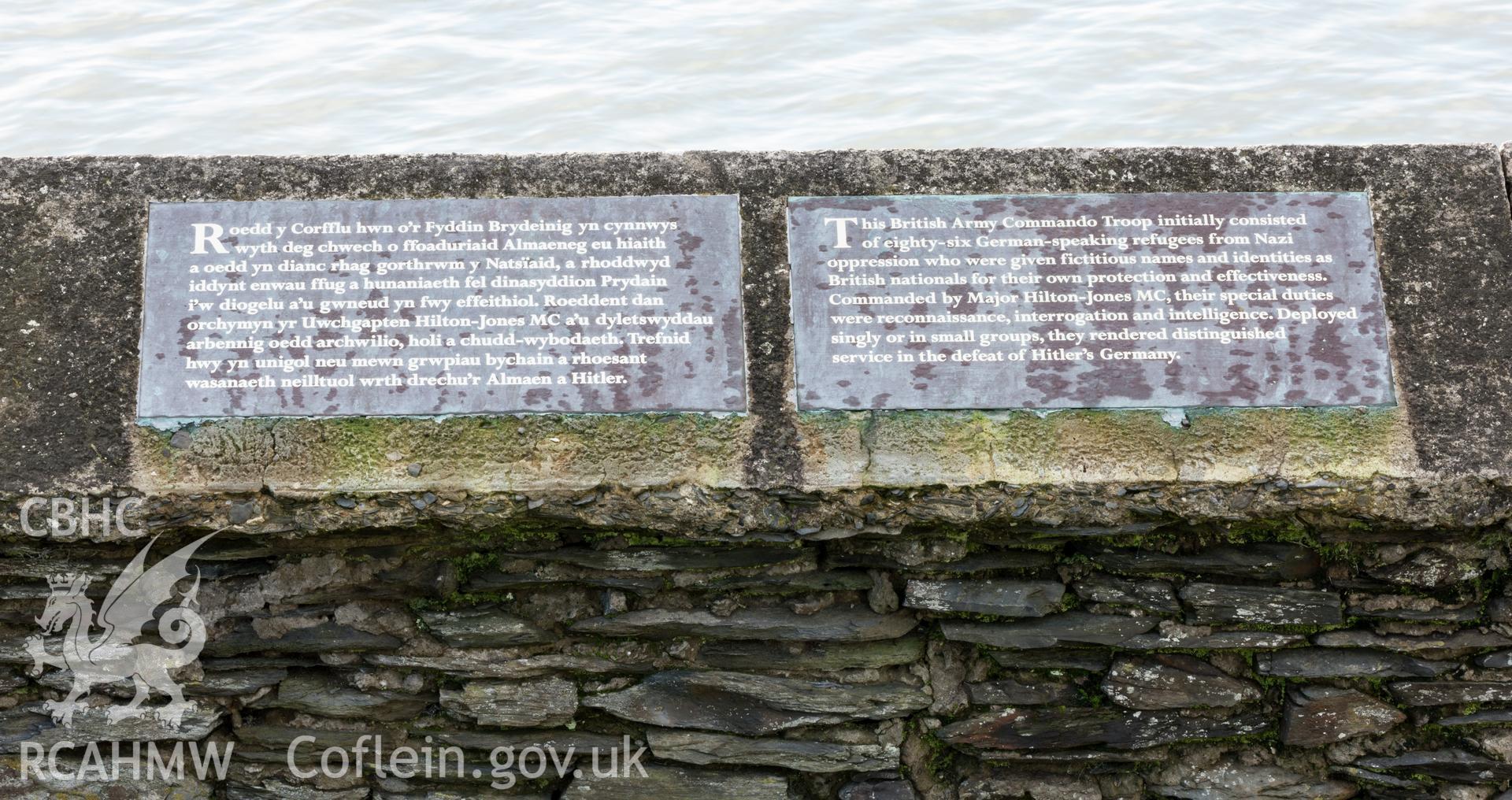 Bilingual text on sea wall explaining memorial