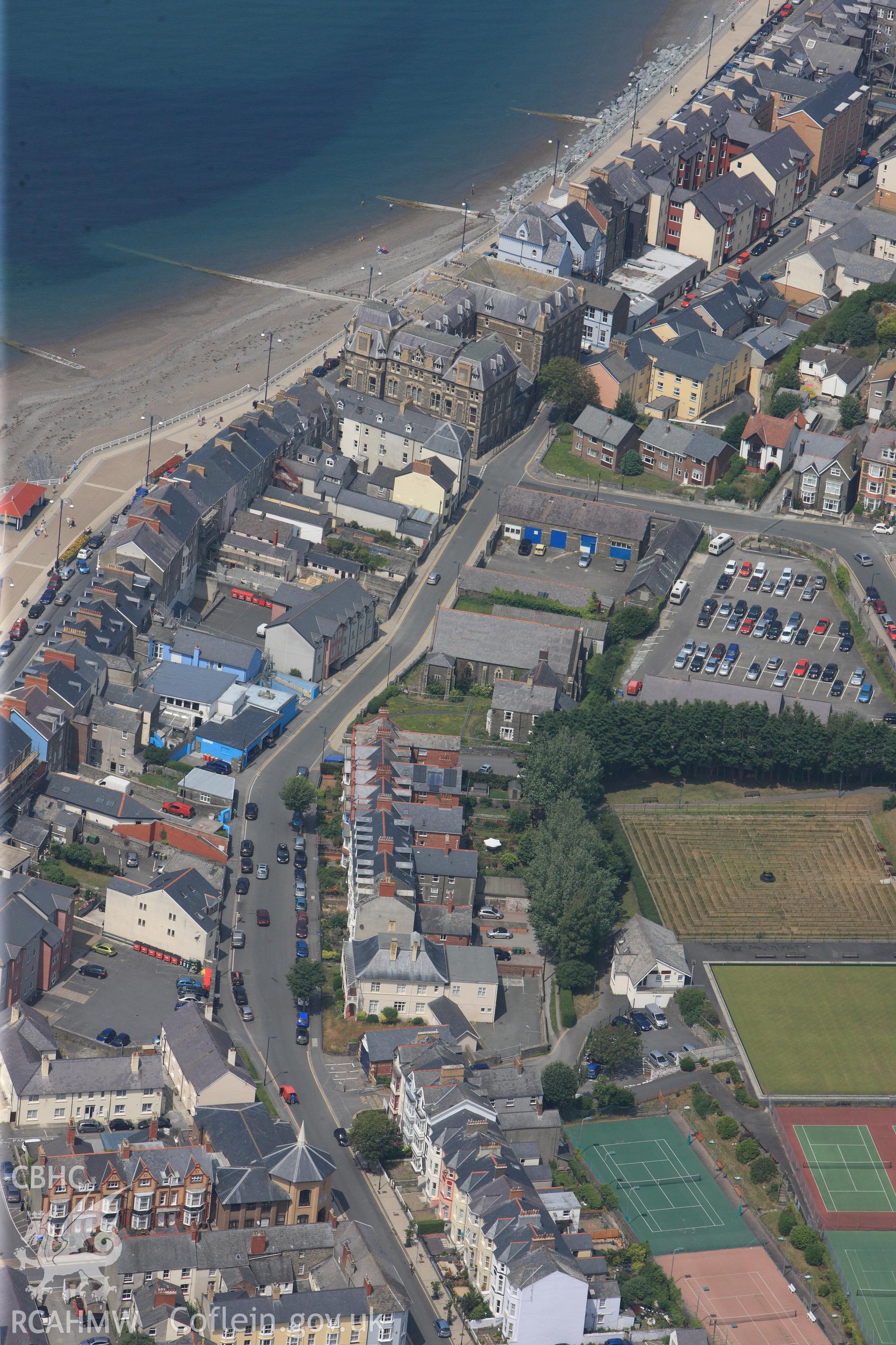View of Aberystwyth including promenade, old County Hall, Catholic Church on Queen's Road, and Bathrock Shelter. Oblique aerial photograph taken during Royal Commission?s programme of archaeological aerial reconnaissance by Toby Driver on 12th July 2013.