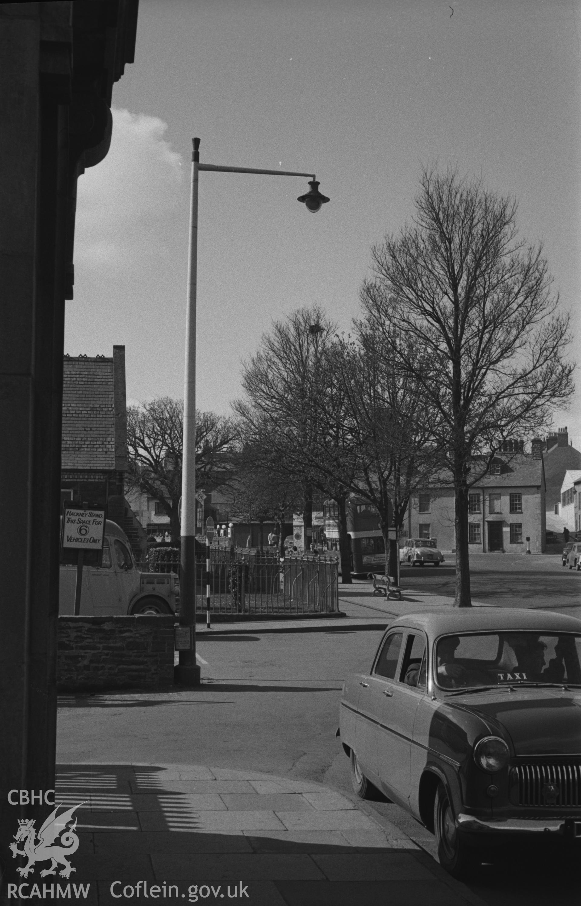 Black and White photograph showing taxi and solitary rook's next in tree outside the County Primary School on Alexander Road, Aberystwyth. Photographed by Arthur Chater in March 1961 from Grid Reference SN 5849 8160, looking west south-west.