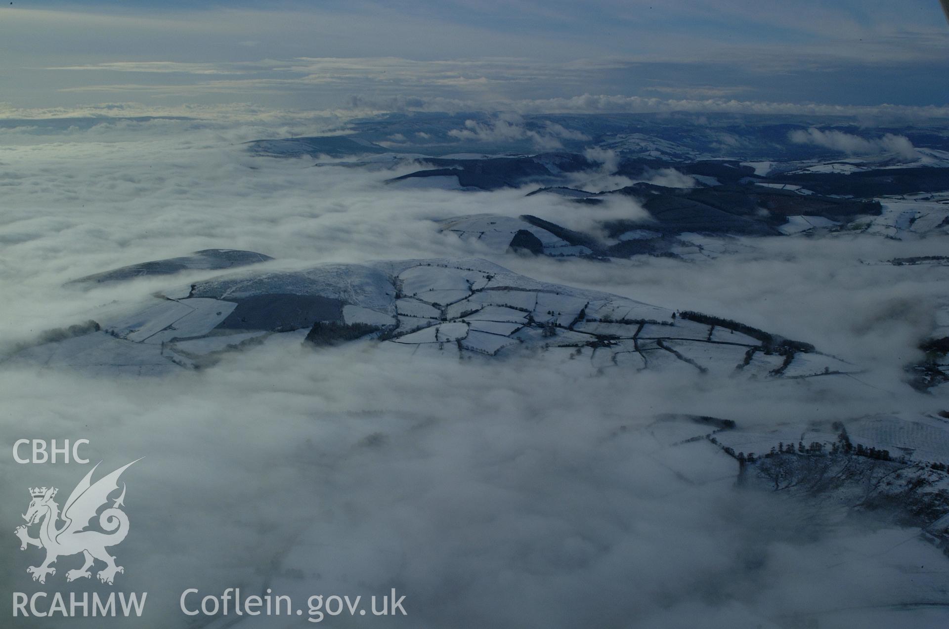 RCAHMW colour oblique aerial photograph of hills and commons south of Llananno, viewed from the north-east under snow and freezing fog. Taken on 19 November 2004 by Toby Driver