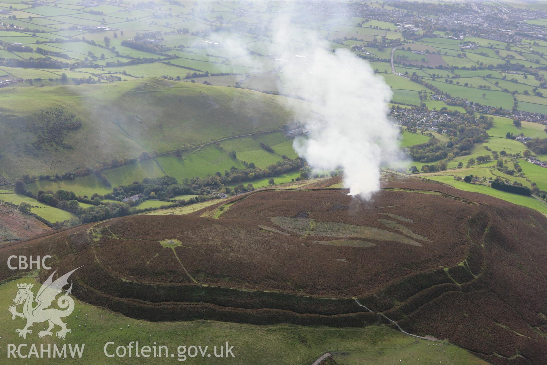 RCAHMW colour oblique aerial photograph of Foel Fenlli Hillfort showing a controlled heather burn. Taken on 13 October 2009 by Toby Driver